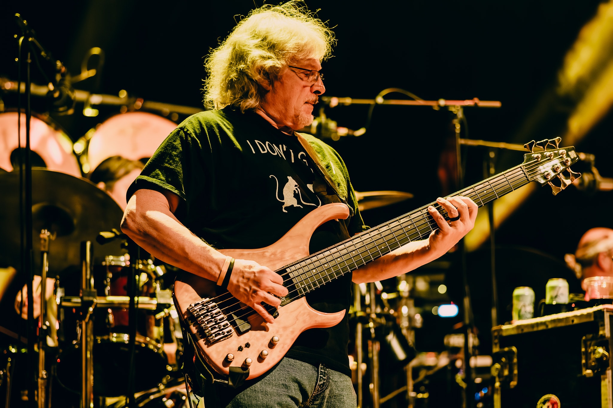 Bassist playing 6-string bass on stage with warm golden stage lighting