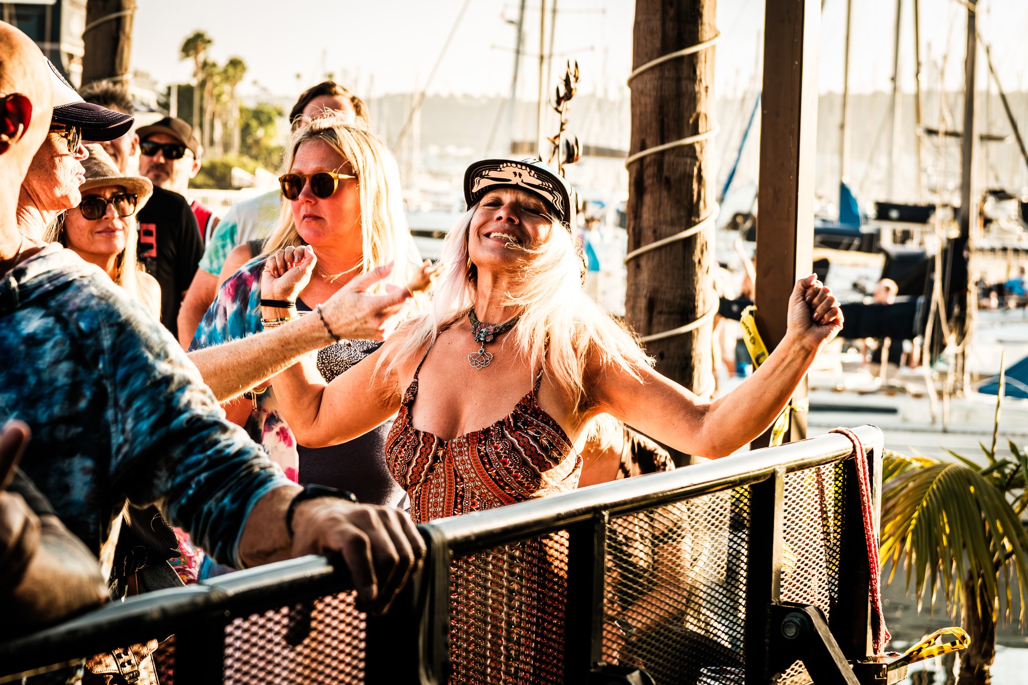 Fan dancing with arms raised at outdoor waterfront concert