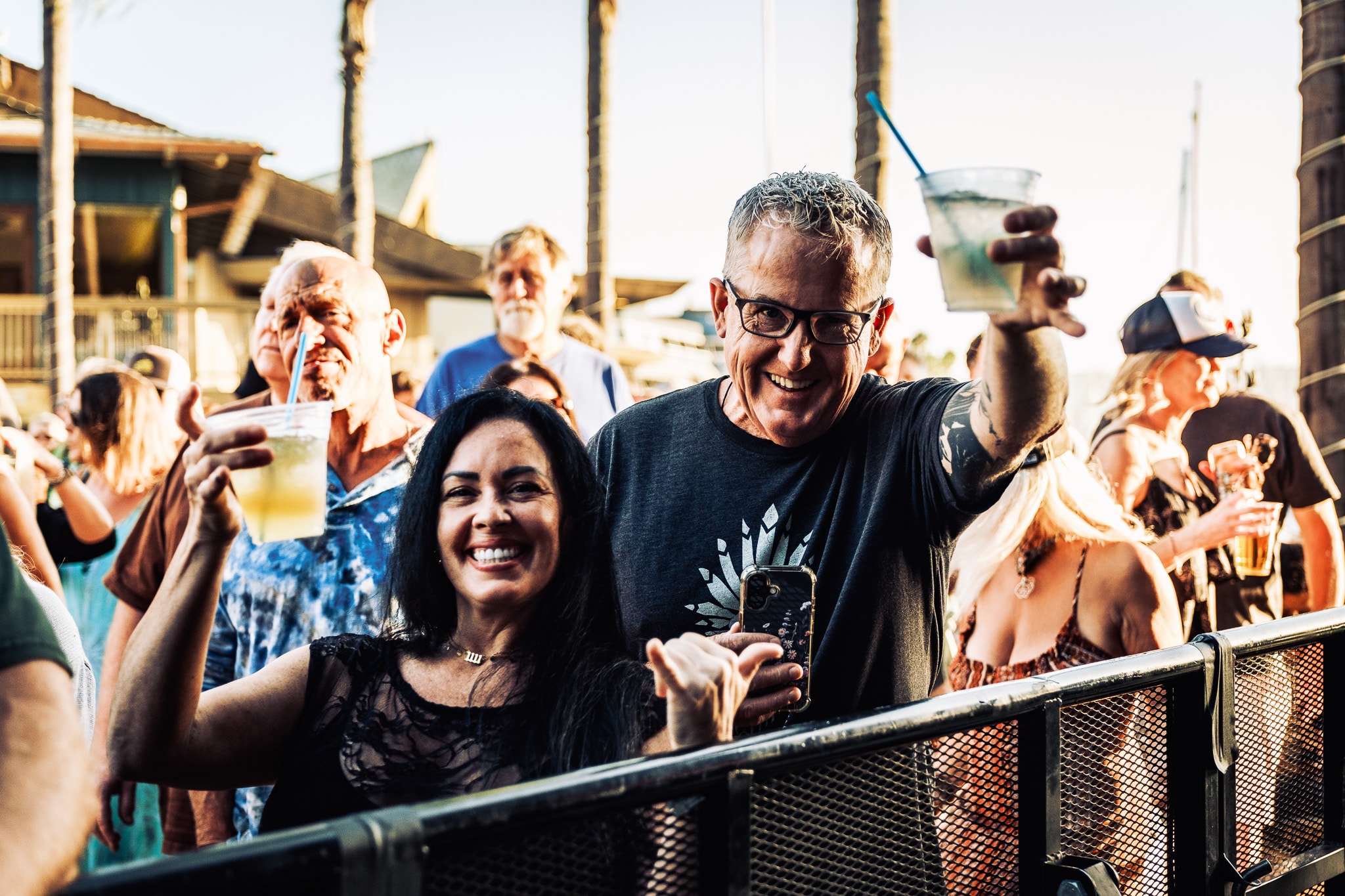 Smiling couple raising drinks at outdoor concert by the bay