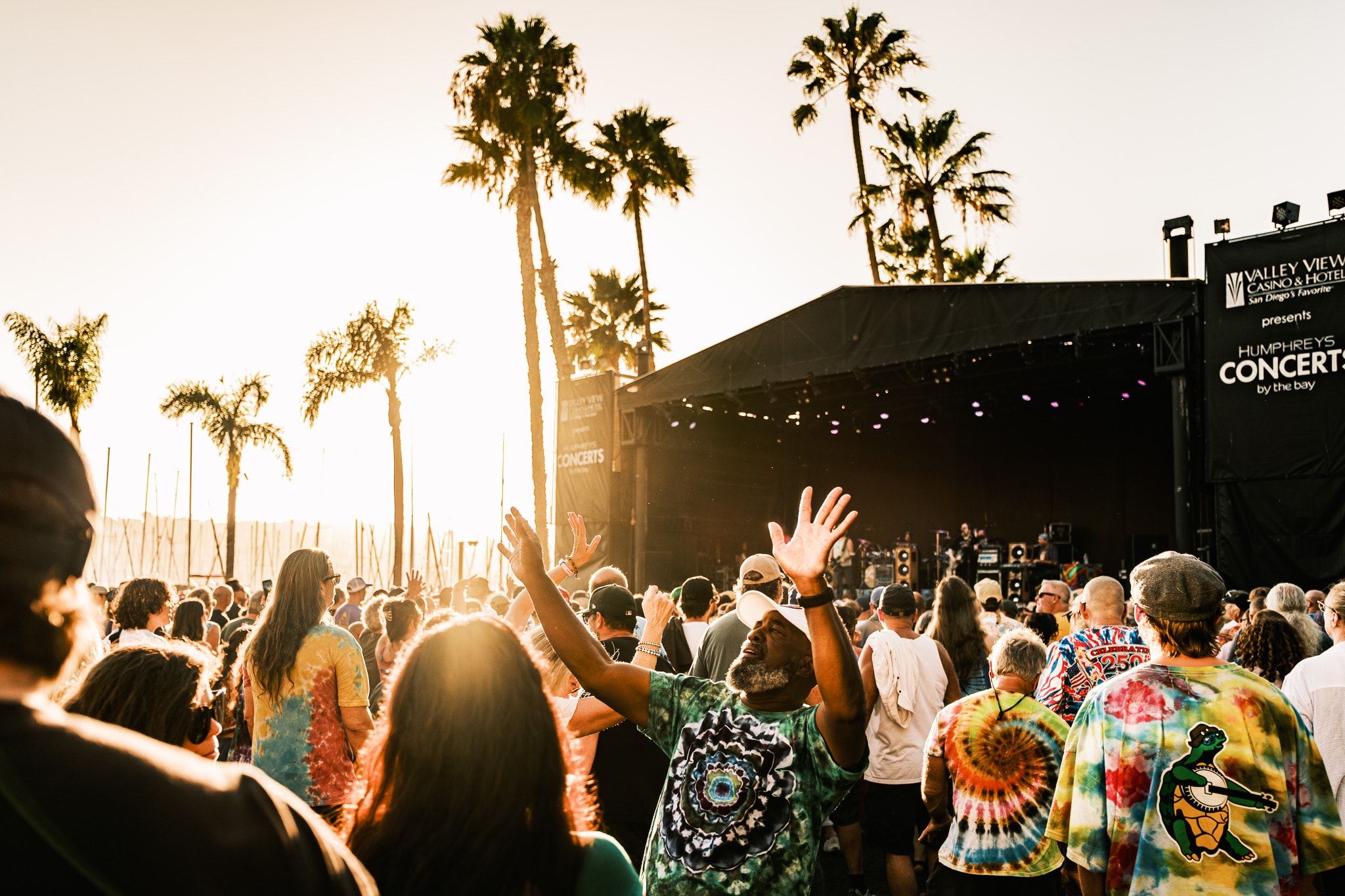Crowd with hands raised at Humphreys Concerts by the Bay at golden hour