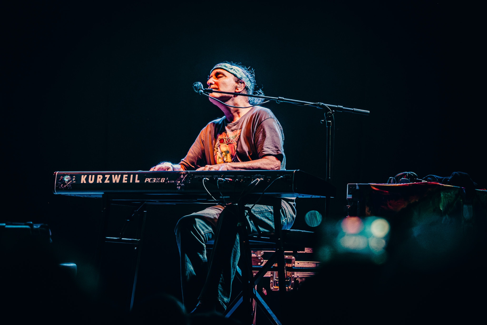 Keyboardist performing on Kurzweil keyboard with moody blue stage lighting