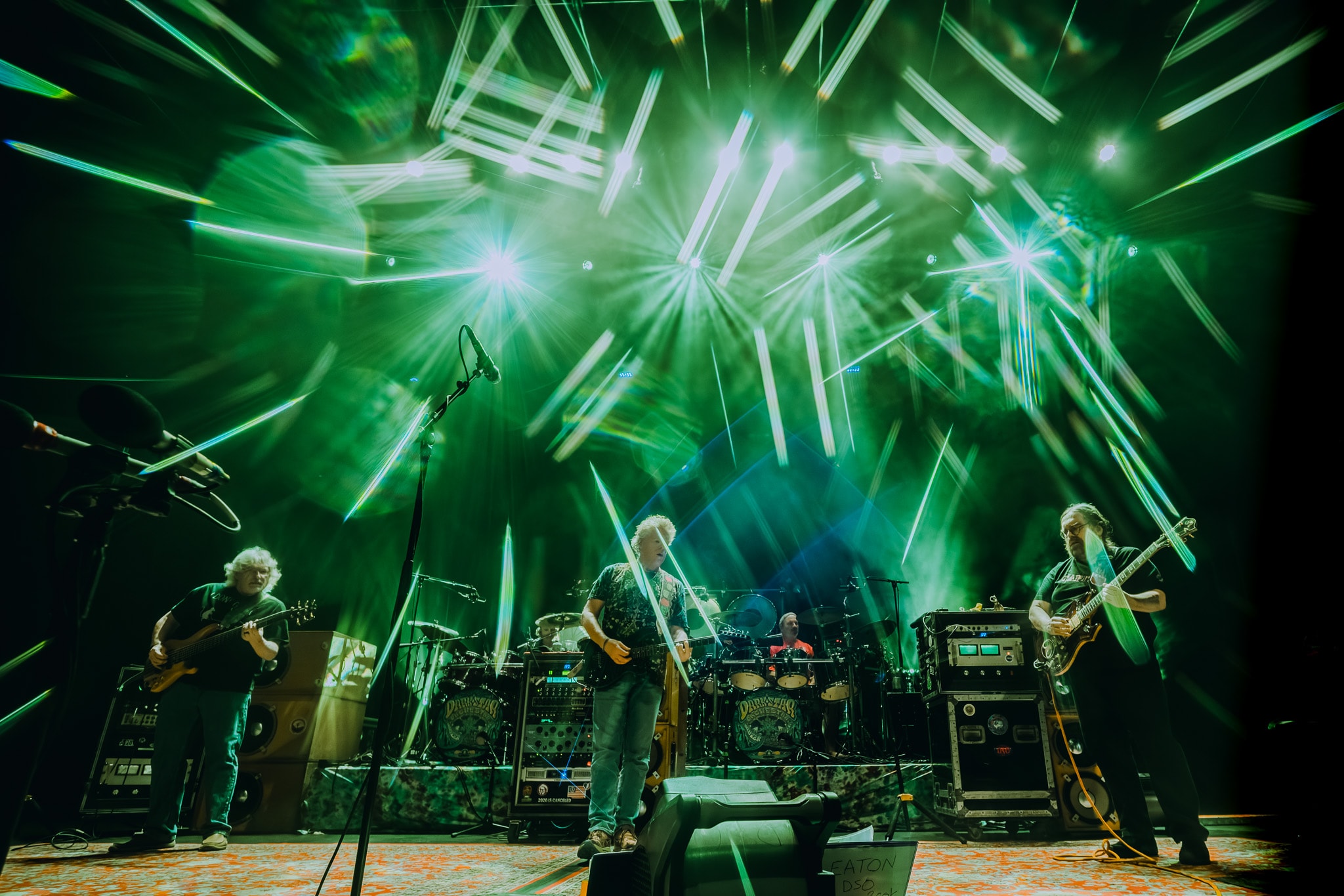 Full band on stage with dramatic green starburst laser light show
