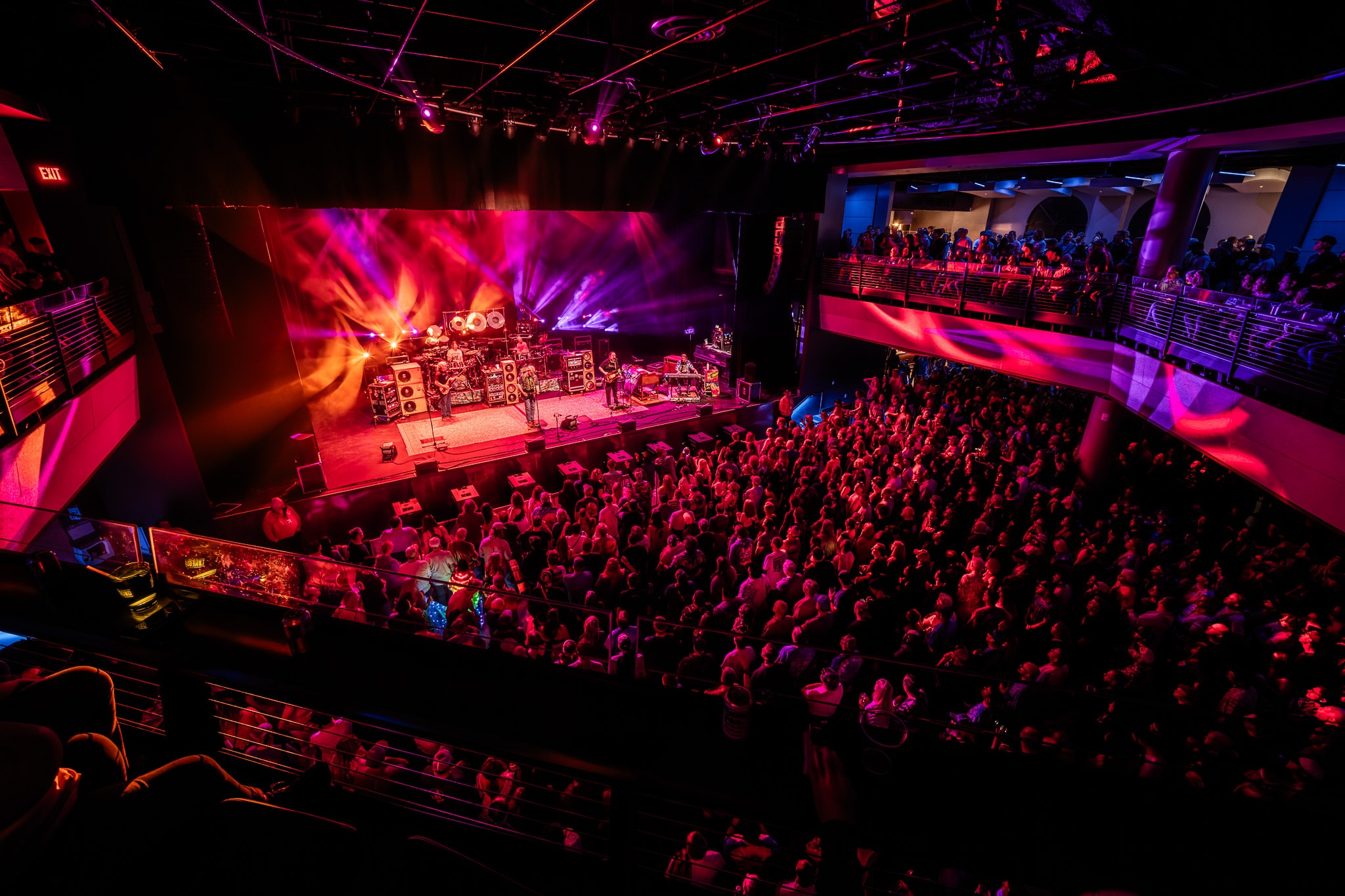 Wide overhead shot of packed venue with pink and purple stage lighting