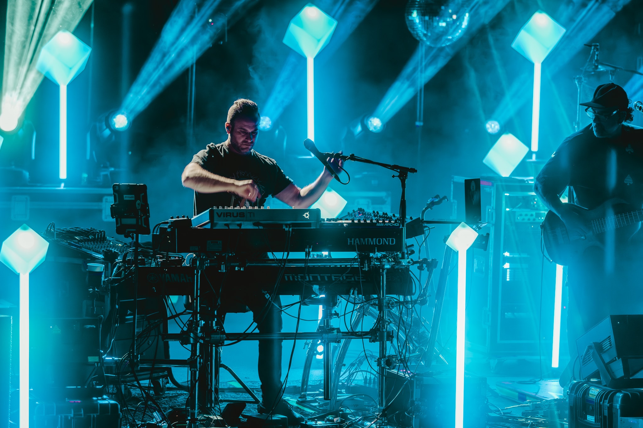 Musician performing keyboard on stage with neon lights
