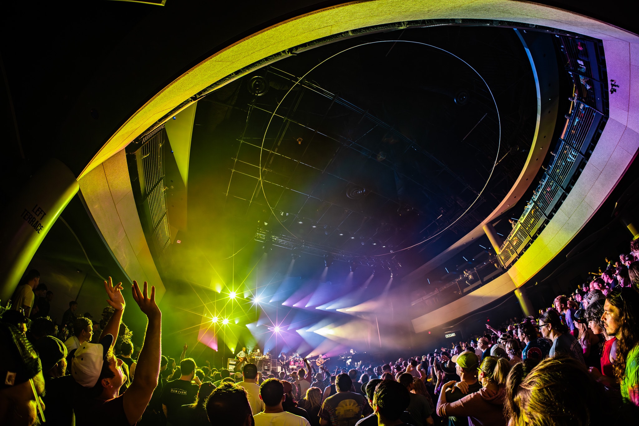 Wide fisheye venue shot with crowd and colorful stage lighting