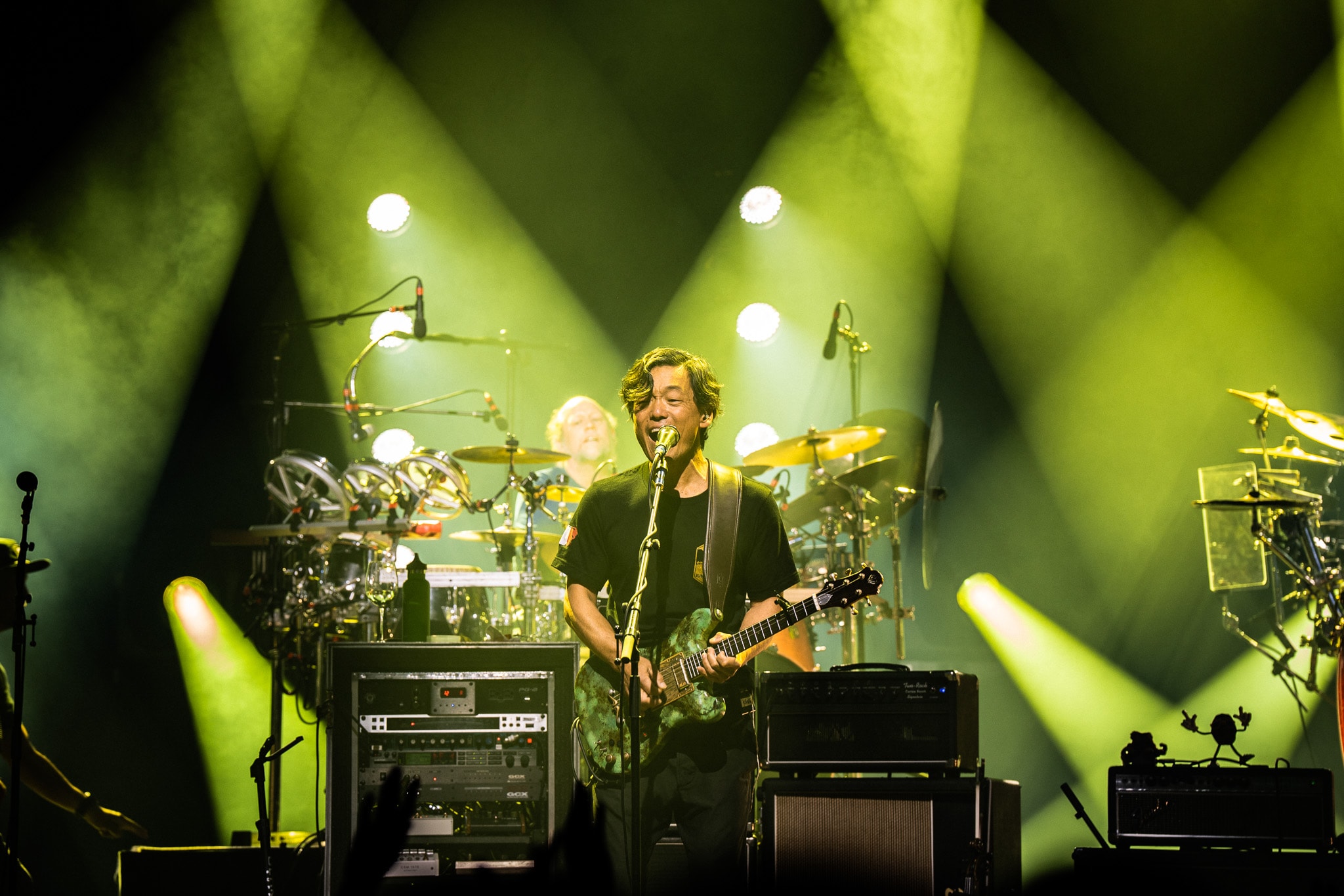 Guitarist and drummer performing with dramatic green stage lights