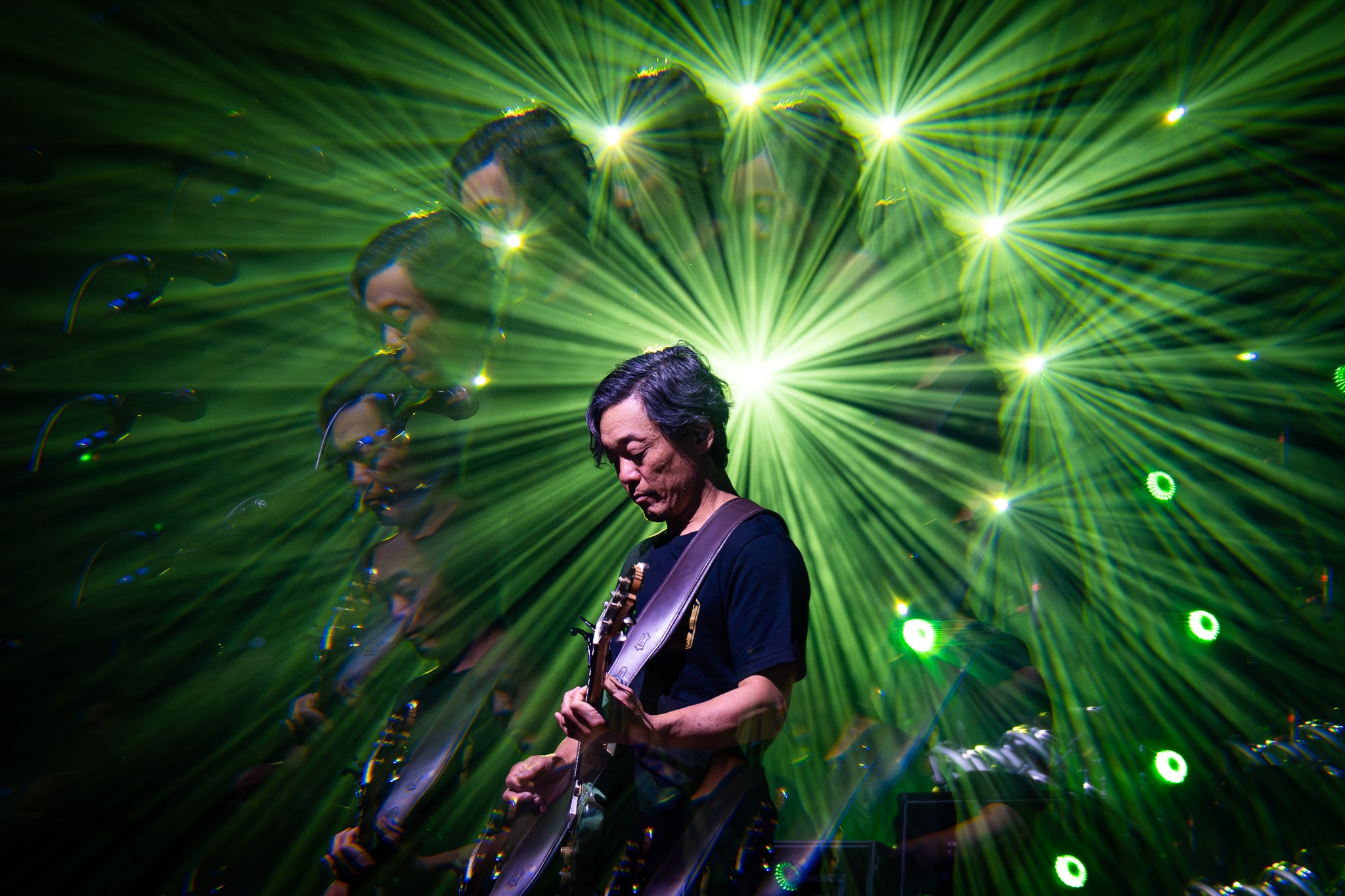 Guitarist performing with dramatic green laser light show