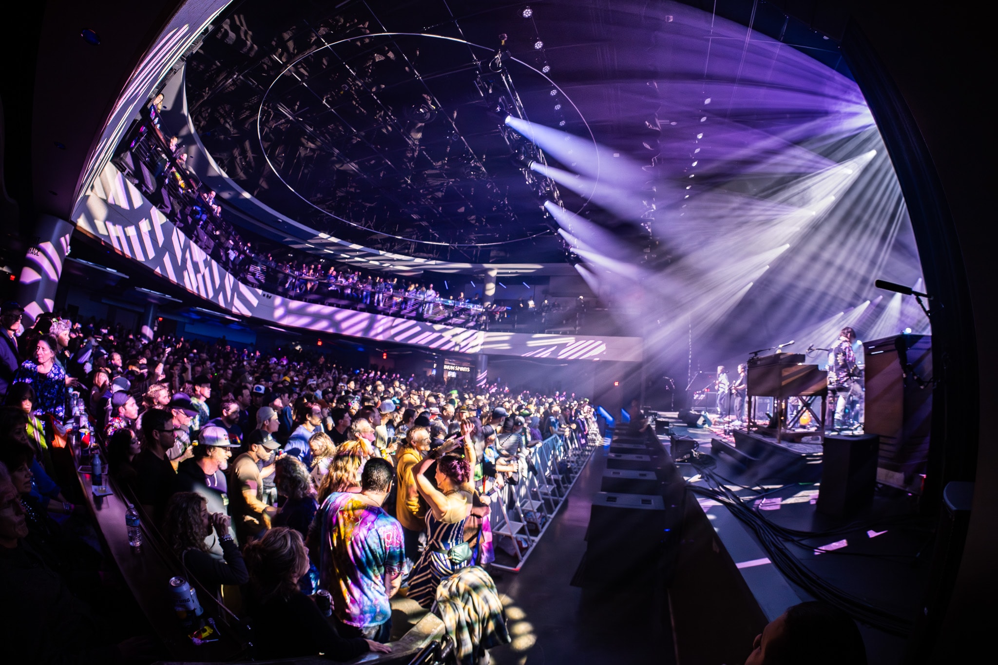 Wide venue shot with crowd and purple stage lighting