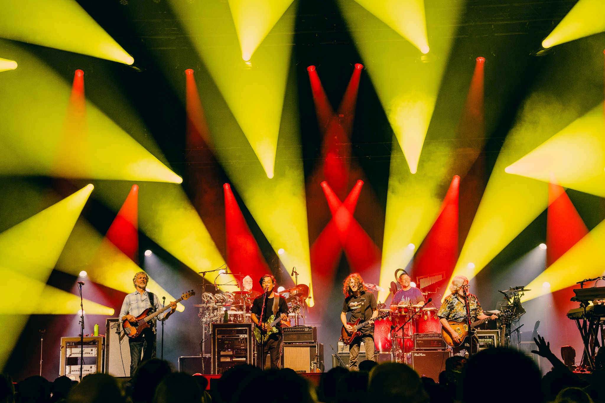 Full band performing with yellow and red crossing light beams