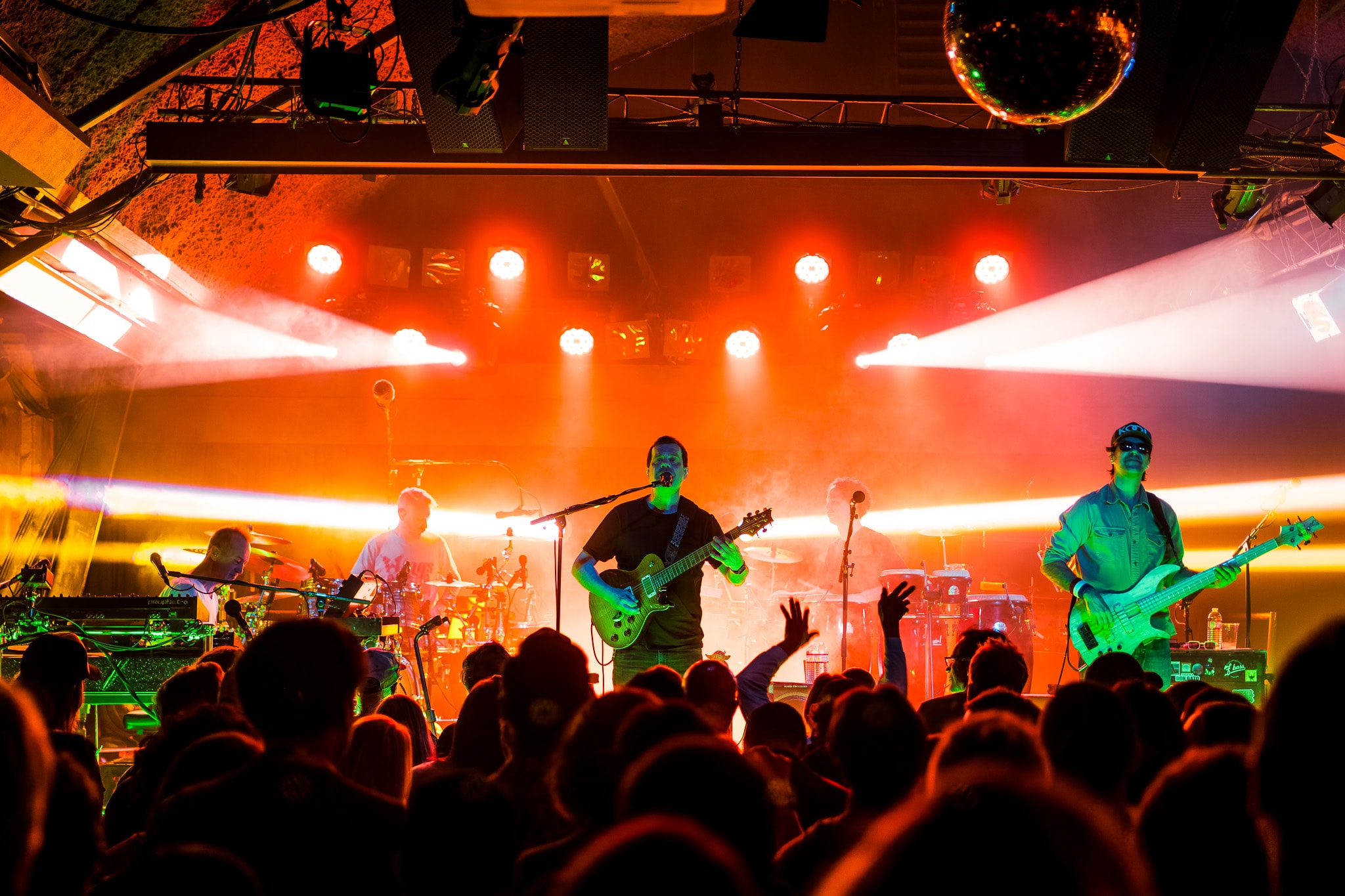 Full band performing with orange and green stage lights