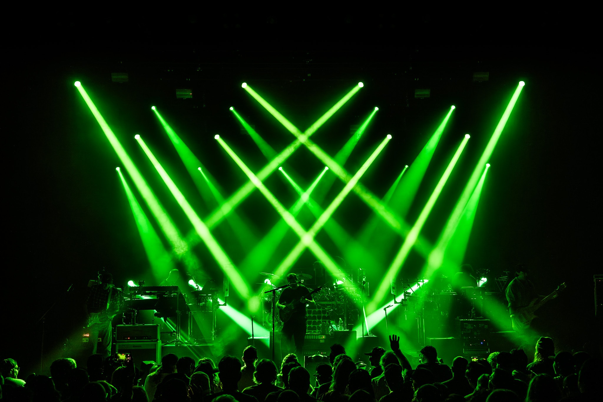 Band silhouetted against dramatic green laser light show