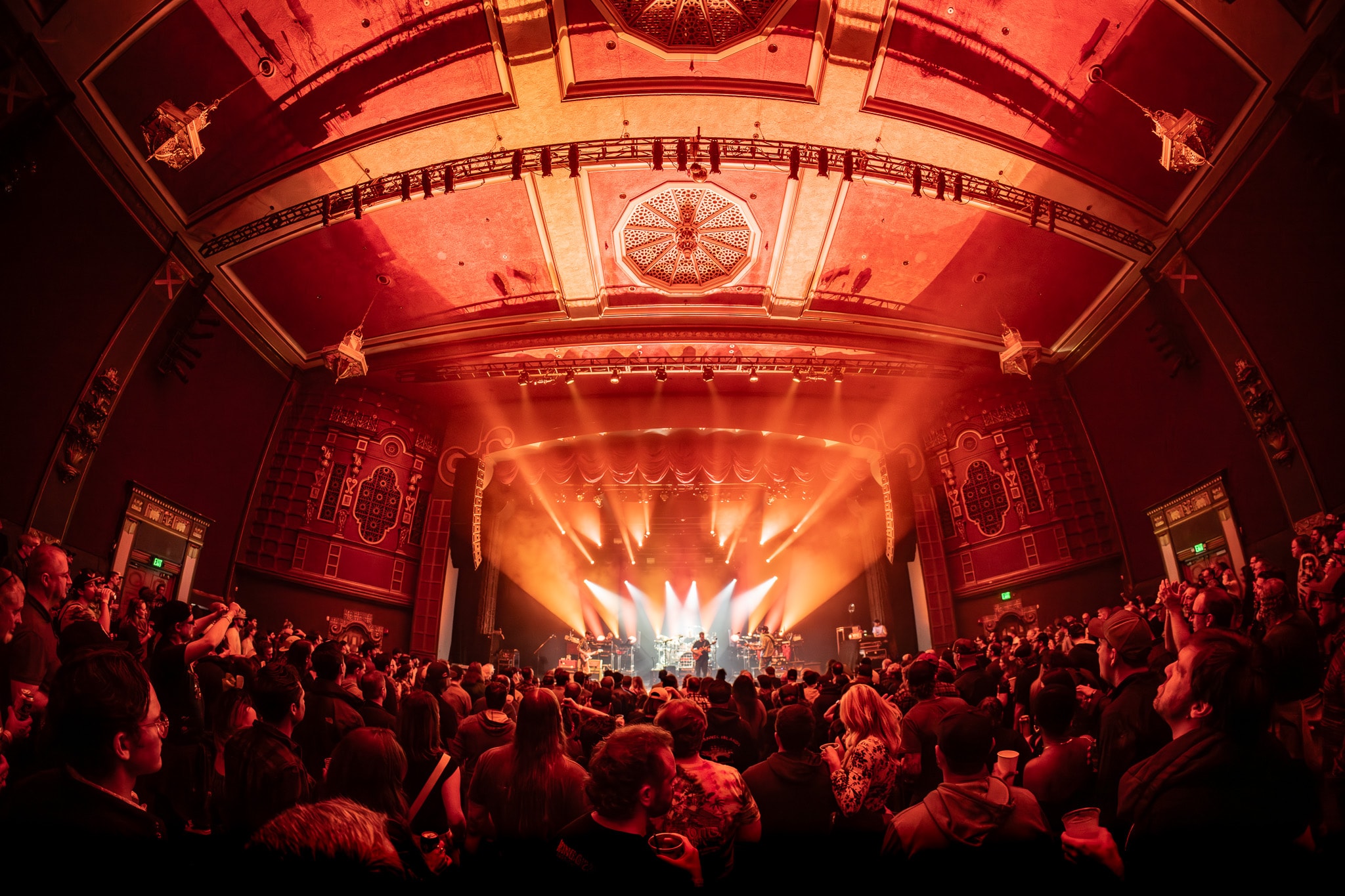 Ornate theater venue with crowd and warm orange stage lighting